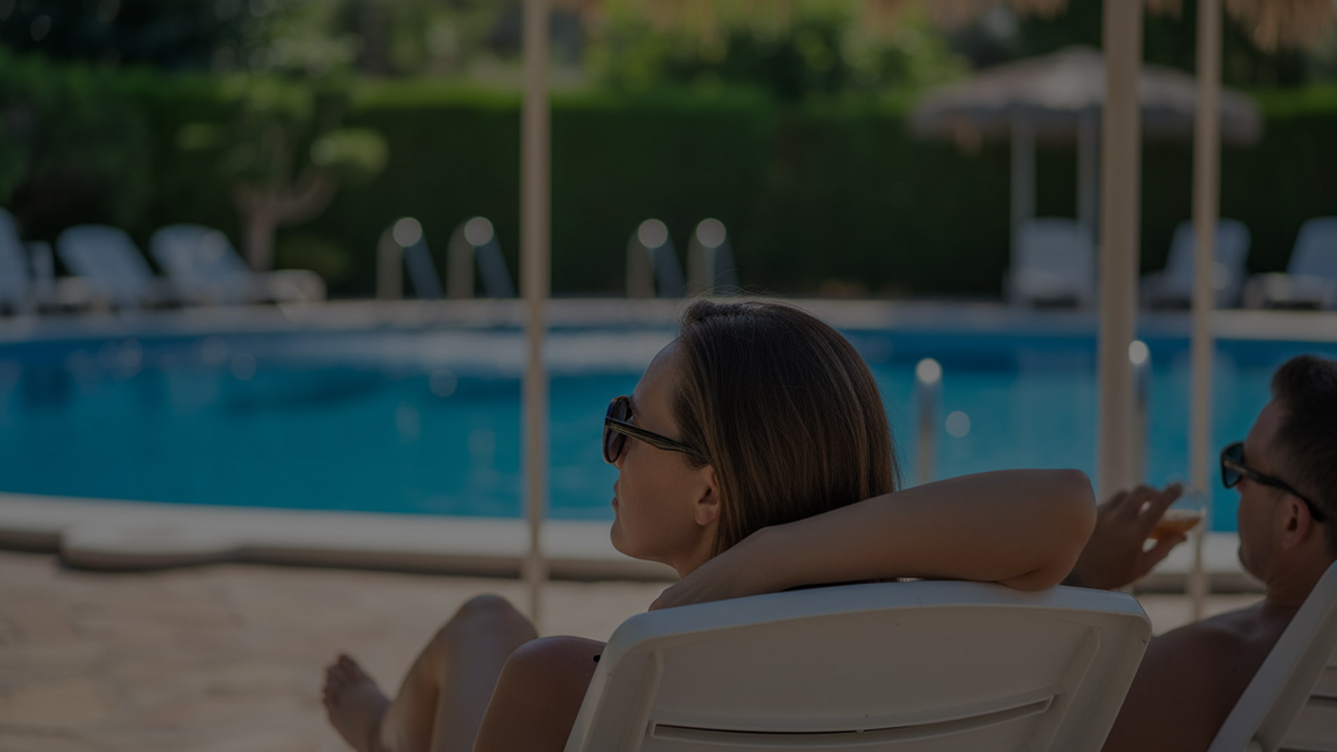 Detail of a couple lying on sun loungers by the hotel swimming pool