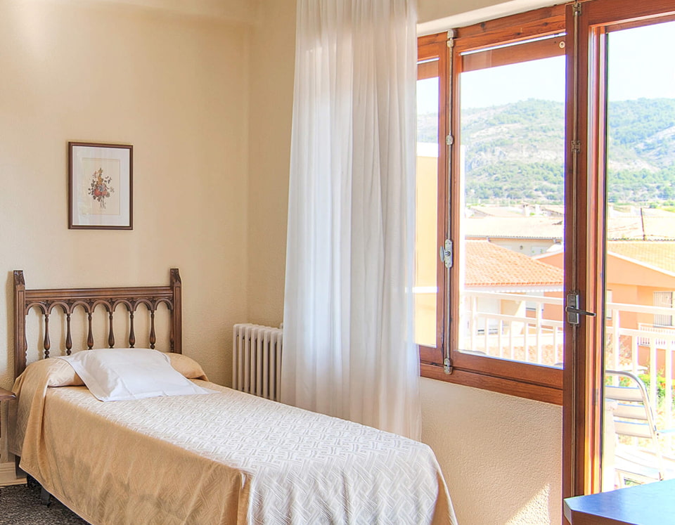 Vista parcial de la habitación, con salida a un balcón con vistas a la ciudad y a las montañas