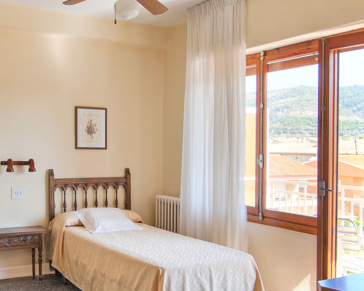 Vista parcial de la habitación, con salida a un balcón con vistas a la ciudad y a las montañas