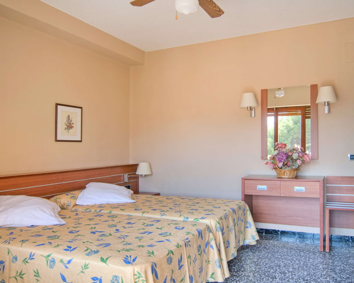 Habitación con dos camas una junto a la otra, con colchas amarillas con flores azules