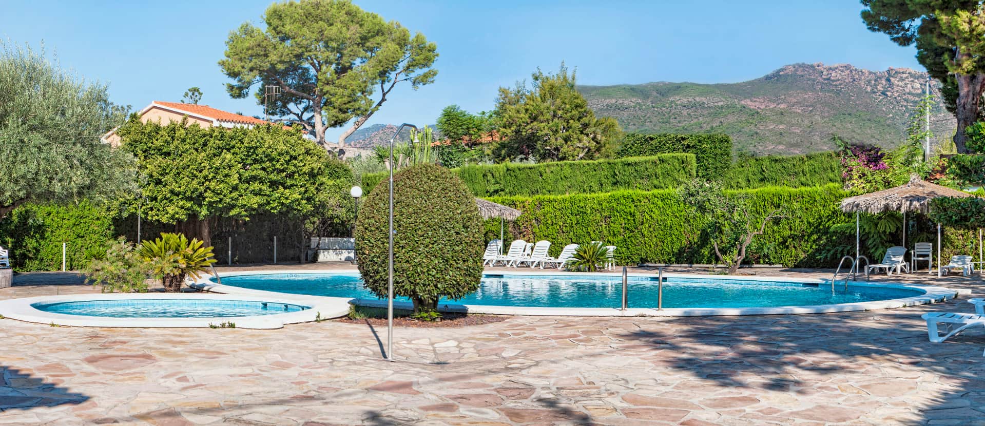 General view of the pool area, with a large pool and a children's pool.
